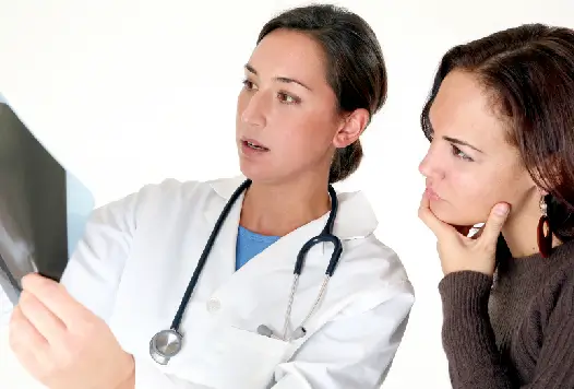 Physician and concerned woman examining X-ray results together, illustrating the indirect costs of chronic illness on daily life.